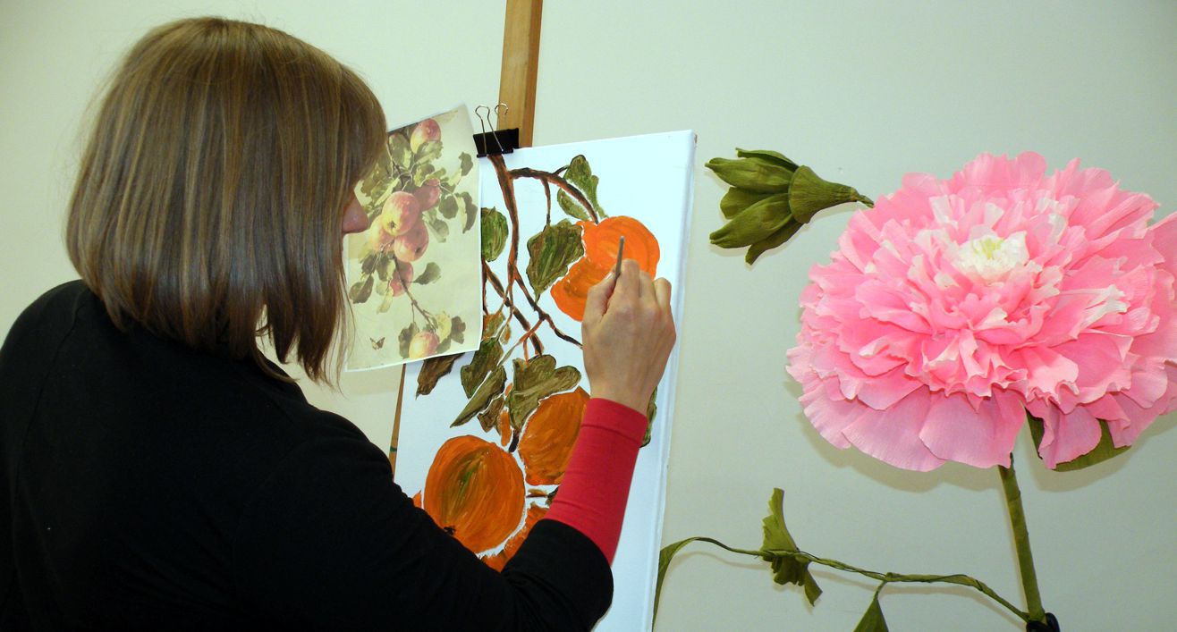 kobieta przy sztaludze malująca kwiaty