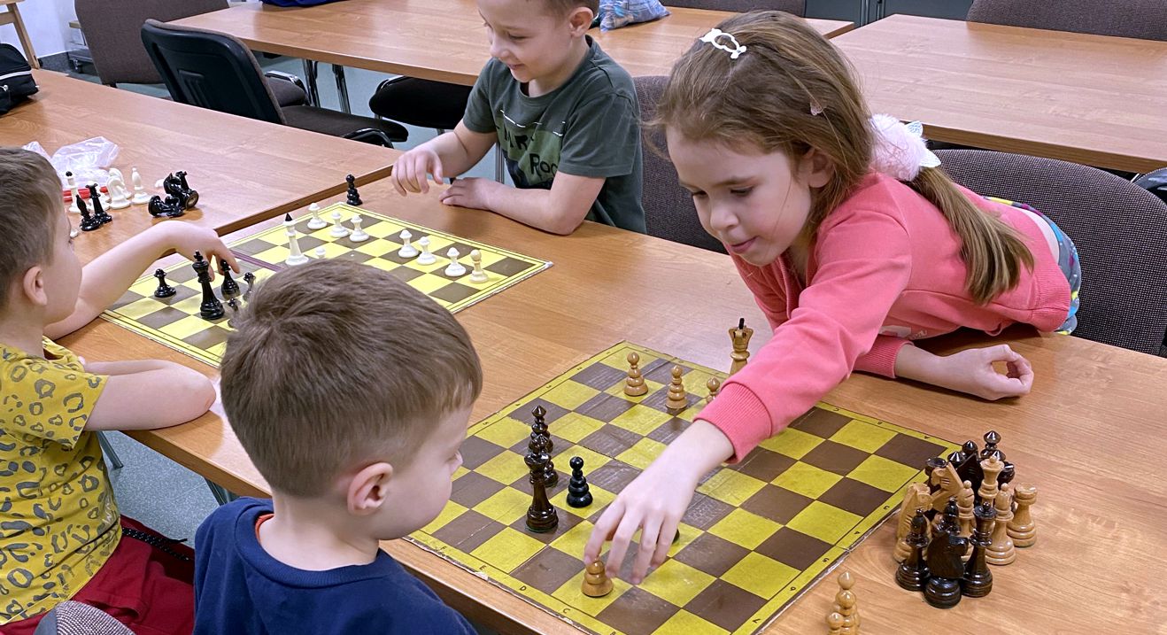 dwie pary dzieci przy szachownicach