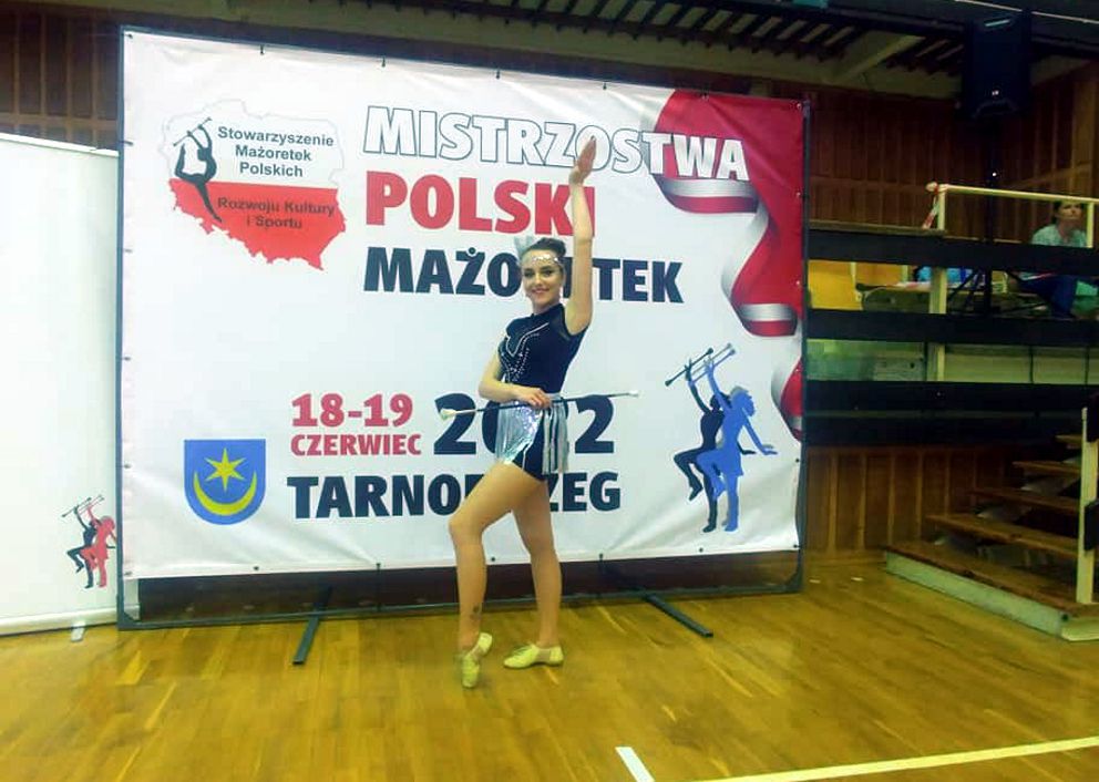 Dziewczyna na tle baneru Mistrzostwa Polski Mażoretek Tarnobrzeg 2022