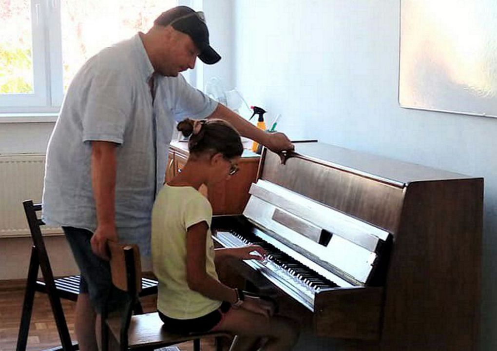 dziewczynka grająca na pianinie obok instruktor