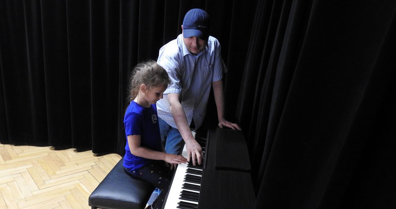 dziewczynka przy pianinie obok instruktor