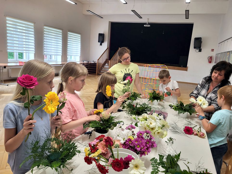 grupa dziei stojących przy stole, po środku kwiaty przygotowane na bukiety